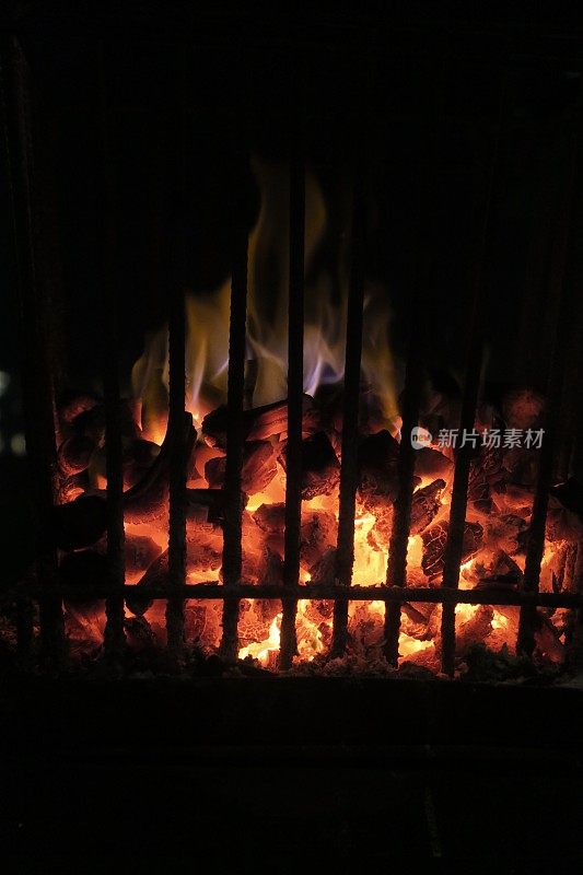 篝火的图像火与火坑火焰在生锈的金属火篮子燃烧木材/柴火，灼热的红色煤炭在室外壁炉/烧烤木炭烧烤加热照片，保持温暖在晚上在花园露营地点的篝火